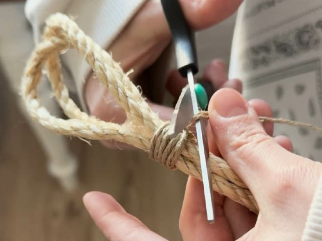 Bindfaden wird um ein Sisalseil gewickelt, damit eine Schlaufe entsteht. Überschuss wird mit einer Schere abgeschnitten