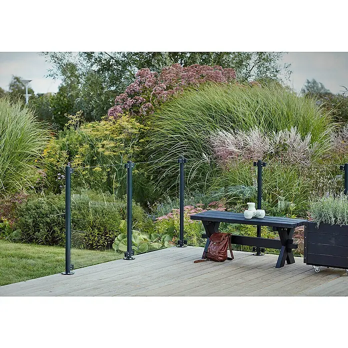 Plus Sichtschutzzaun für runde Pfosten - 90 x 91 cm, Transparent, 8,7 mm - Eine moderne Terrassengestaltung mit stilvollem Geländer, dunkler Holzbank und üppiger Bepflanzung für eine entspannte Atmosphäre im Freien.