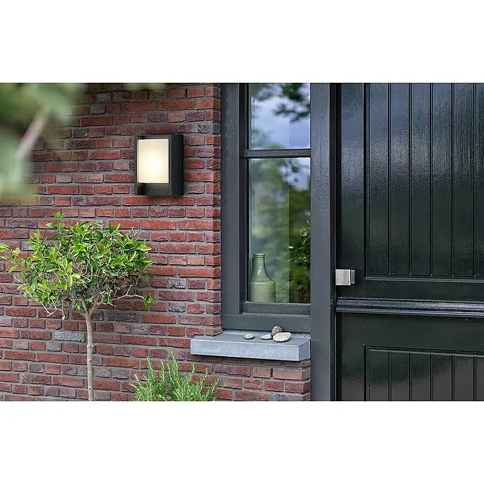 Philips Arbour LED-Außenwandleuchte - 3,8 W, 16,5 x 7,5 x 22 cm, IP44 - Eine moderne Außenwandleuchte in einem schlichten, rechteckigen Design, die an einer roten Backsteinmauer neben einem Fenster montiert ist.