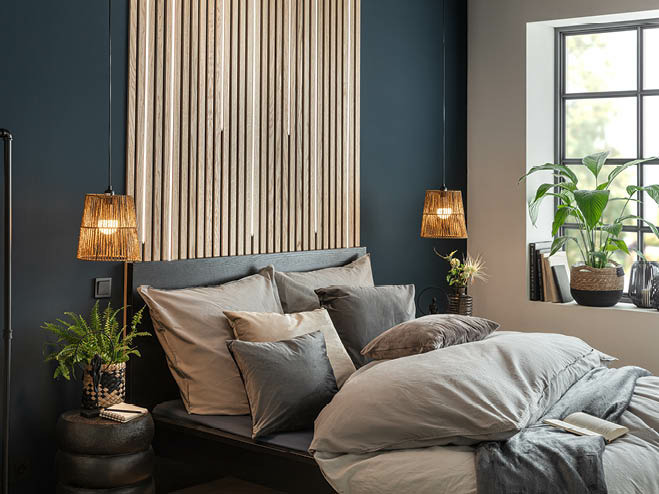 Harmonisch gestyltes Bett, Paneel an der Wand und dunkelblaue Wandfarbe