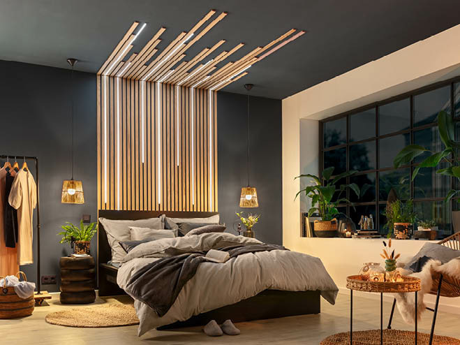 Blick auf ein Schlafzimmer bei Nacht. Die LED-Leisten in den Wandpaneele leuchten