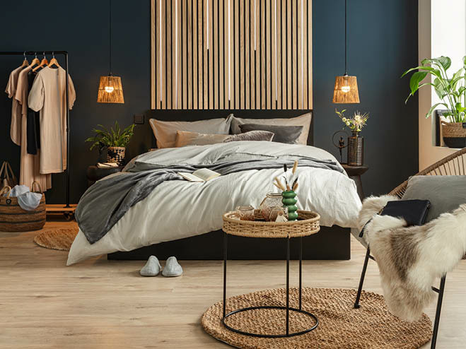Blick auf das Bett, im Vordergrund ein Teppich, Beistelltisch und ein Sessel