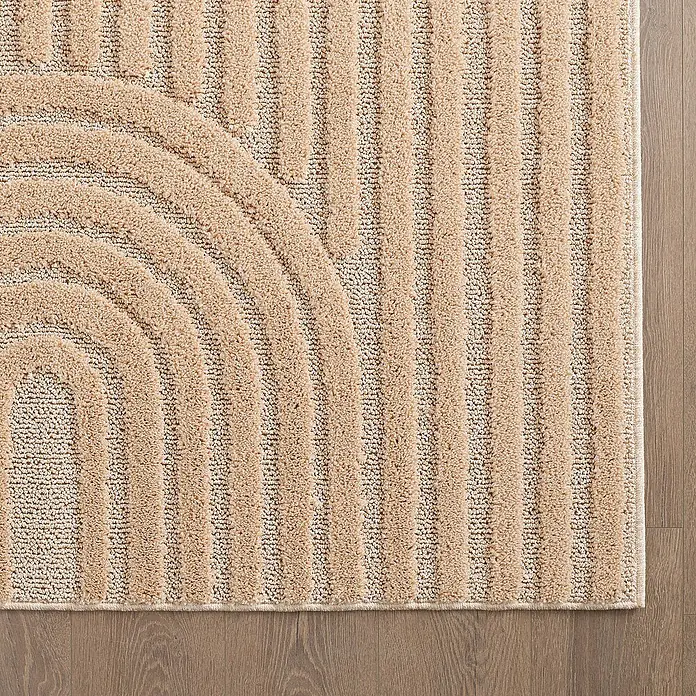 Kurzflorteppich Art - Rosa, 340 x 240 cm, 100 % Polypropylen - Nahaufnahme eines beigen Teppichs mit geometrischem Muster und Holzfußboden im Hintergrund.