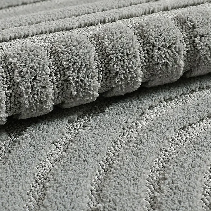 Kurzflorteppich Art - Silber, 290 x 200 cm, 100 % Polypropylen - Nahaufnahme eines gerollten, grauen Teppichs mit weicher Textur, ideal für Badezimmer oder Schlafzimmer.