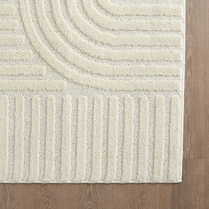 Kurzflorteppich Art - Creme, Durchmesser: 80 cm, 100 % Polypropylen - Nahaufnahme eines cremefarbenen Teppichs mit geometrischen Mustern auf einem Holzboden.