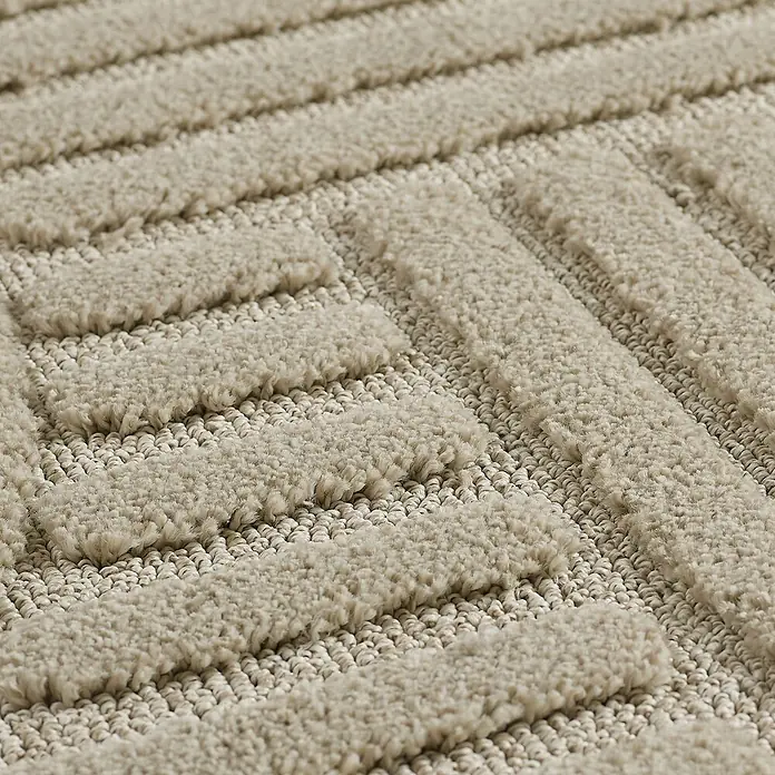 Kurzflorteppich Art - Beige, 150 x 80 cm, 100 % Polypropylen - Nahaufnahme eines beigen Teppichs mit geometrischen Mustern, der Textur und Design hervorhebt.