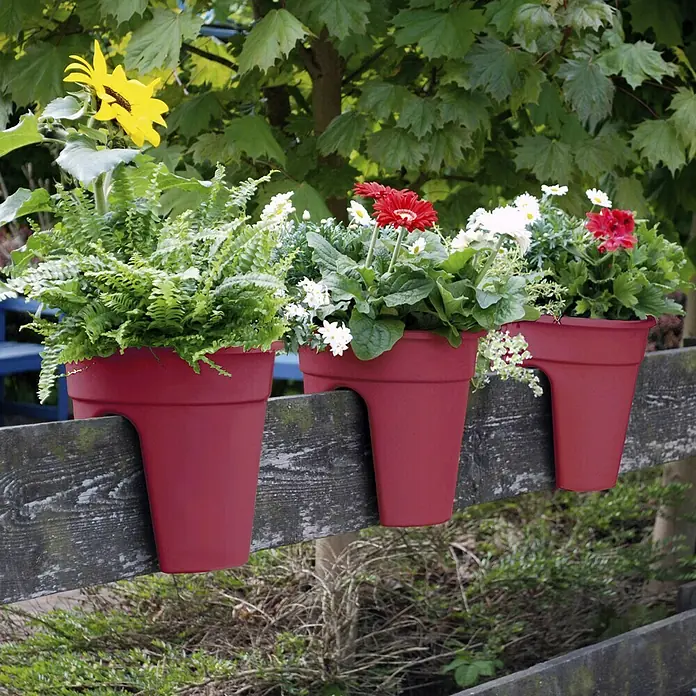 KHW Geländertopf FlowerclipAußenmaß (Ø x H): 27 x 27,5 cm, Kunststoff, Beere - Drei rote Blumenkästen hängen an einem Holzzaun und sind mit bunten Blumen und Pflanzen bepflanzt.