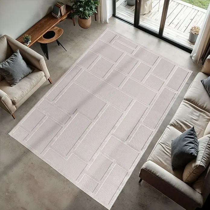 Kurzflorteppich Doha 1657Creme, 290 x 200 cm, 100 % Polypropylen - Ein beiger Teppich mit geometrischen Mustern liegt in einem modernen Wohnzimmer mit Sofa und Sessel.