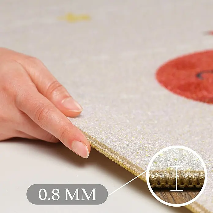 Kinderteppich Play 2019 - Beige, 150 x 100 cm, 100 % Polypropylen - Eine Hand hält den Rand einer dünnen, hellen Matte mit einem Einsatz, der die 0,8 mm Dicke zeigt.