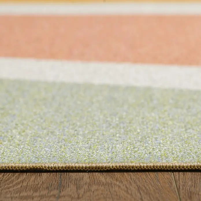 Kinderteppich Play 2020 - Bunt, 150 x 100 cm, 100 % Polypropylen - Detailansicht eines Teppichs mit bunten Streifen und einer dekorativen Bordüre, der auf einem Holzboden liegt. Das Produkt wirkt hochwertig.