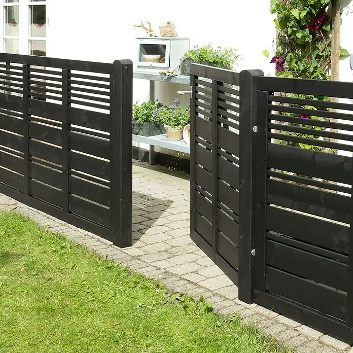 Plus Gartentor Silence inkl. Beschläge - 100 x 110 cm, Schwarz, Holz - Schwarzer Holzzaun mit horizontalen Lamellen und einem offenen Tor, das zu einem Garten mit Rasen führt, mit Pflanzen und einem Regal im Hintergrund.