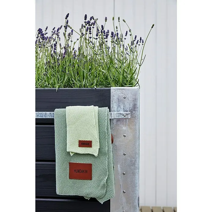 Plus Pflanzkasten Cubic - Außenmaß (L x B x H): 120 x 50 x 95 cm, Holz, Schwarz/Silber - Zwei hellgrüne gestrickte HUMDAKIN Tücher mit braunen Etiketten hängen über einem schwarzen Pflanzgefäß mit Lavendel.