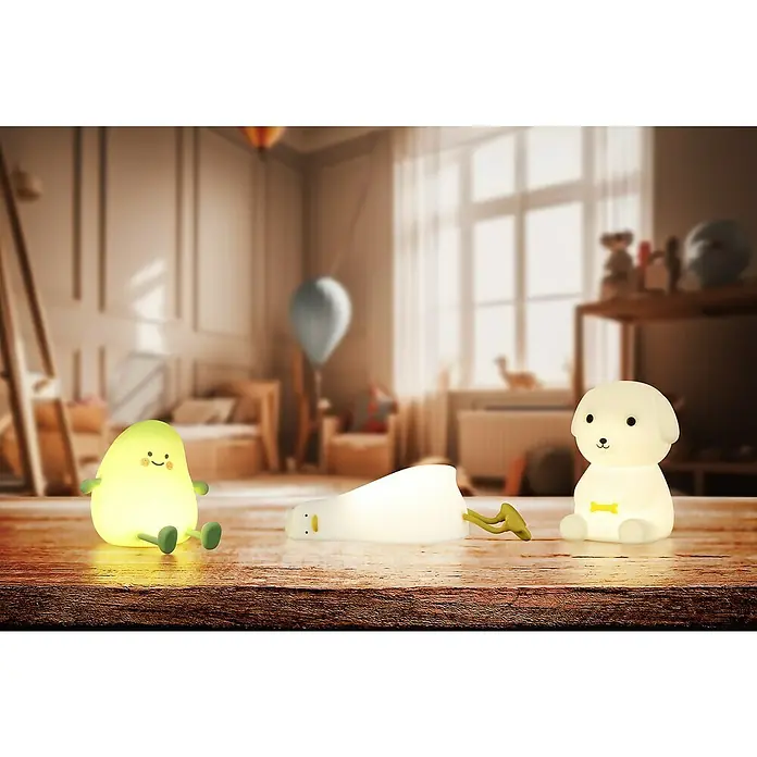 FHL easy LED-Nachtlicht Leo - 0,6 W, L x B x H: 9 x 10 x 13,5 cm, RGBW, Welpe Leo - Drei leuchtende Nachtlichter (Avocado, Ente, Hund) auf einer Holzoberfläche in einem verschwommenen Schlafzimmer.