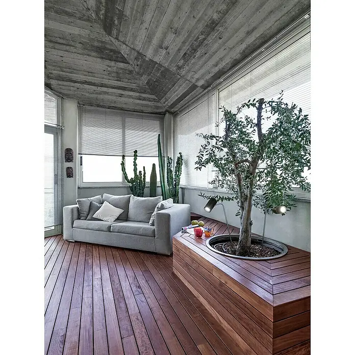 FHL easy Magnetic LED-Außenstrahler 4 in 1 - Sandschwarz, Höhe: 57 cm, IP54 - Moderner Wintergarten mit grauem Sofa, eingebautem Holzpflanzgefäß mit Baum und Betondecke.