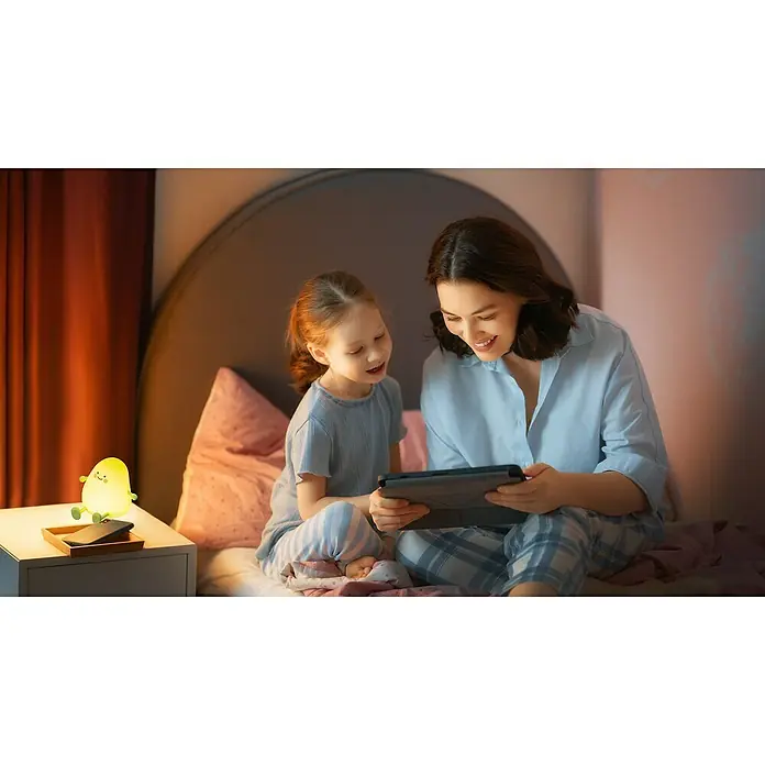 FHL easy LED-Nachtlicht Lia - 0,4 W, L x B x H: 12,2 x 12,2 x 11,6 cm, Warmweiß, Avocado Lia - Ein niedliches, leuchtendes, birnenförmiges Nachtlicht mit freundlichem Gesicht spendet weiches gelb-grünes Licht auf einem Nachttisch.