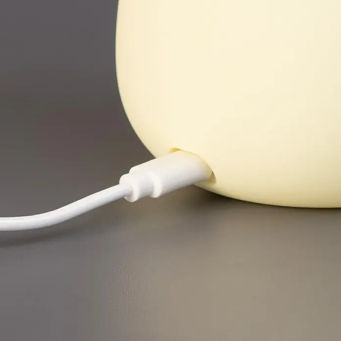 FHL easy LED-Nachtlicht Lia - 0,4 W, L x B x H: 12,2 x 12,2 x 11,6 cm, Warmweiß, Avocado Lia - Nahaufnahme eines weißen Ladekabels, das in ein hellgelbes Gerät gesteckt ist.