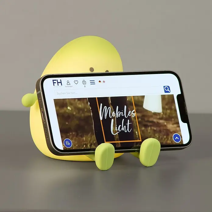 FHL easy LED-Nachtlicht Lia - 0,4 W, L x B x H: 12,2 x 12,2 x 11,6 cm, Warmweiß, Avocado Lia - Gelber Avocado-Handyständer, der ein Smartphone horizontal hält.