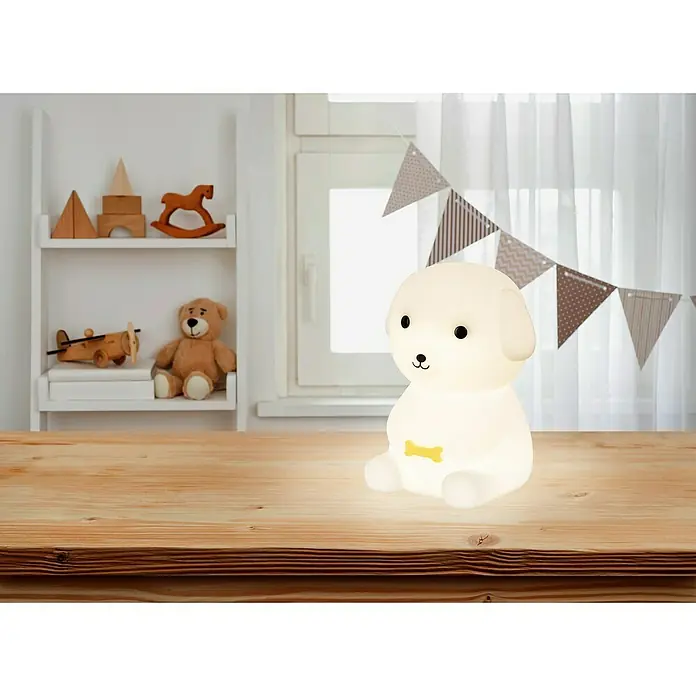 FHL easy LED-Nachtlicht Leo - 0,6 W, L x B x H: 9 x 10 x 13,5 cm, RGBW, Welpe Leo - Ein leuchtendes weißes Hund-Nachtlicht mit gelbem Knochen-Detail auf Holztisch im Kinderzimmer.