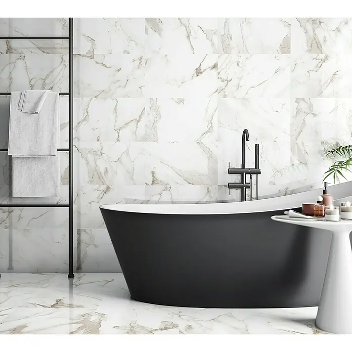 Revestimiento de pared Arezzo - 33 x 55 cm, Oro, Brillante - Elegante baño con bañera negra exenta, azulejos marmoleados y un toallero.