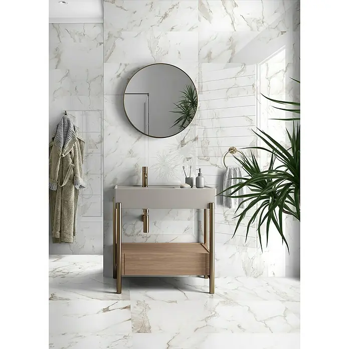 Halcón Revestimiento de pared Imperium - 30 x 90 cm, Oro, Brillante - Un baño moderno con un elegante lavabo con detalles dorados, situado bajo un espejo redondo. Los azulejos con efecto mármol aportan un toque de lujo.