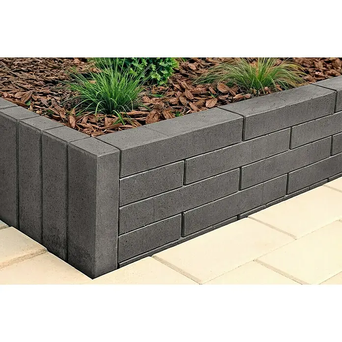 Christoph C-Line Palisade XL - 60 x 15 x 10 cm, Anthrazit, Beton - Hochbeet aus dunkelgrauen Betonsteinen, gefüllt mit Pflanzen und Mulch, grenzt an helle Pflastersteine.