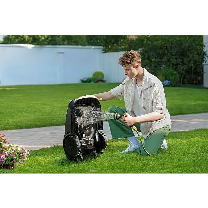 Mova Mähroboter 600 Plus - 600 m², Schnittbreite: 20 cm, Laser-gestützte Navigation, LiDAR - Ein junger Mann reinigt einen Roboter-Rasenmäher mit einem Wasserschlauch im Garten.