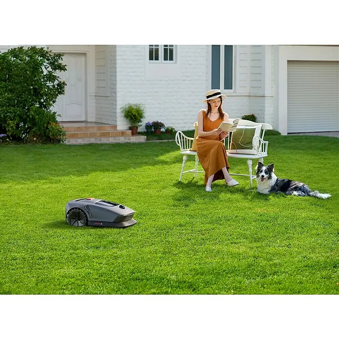 Mova Mähroboter 600 Plus - 600 m², Schnittbreite: 20 cm, Laser-gestützte Navigation, LiDAR - Eine Frau entspannt im Garten, während ein Rasenmähroboter das Gras schneidet. Im Vordergrund ist der Roboter klar zu sehen.