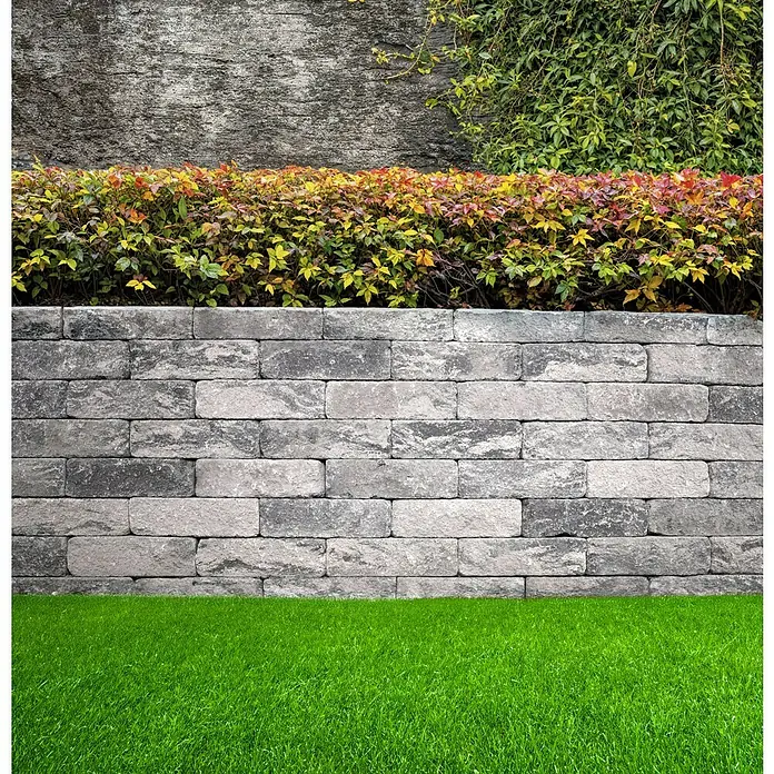 EHL Mauerstein Anzio Light - 50 x 18 x 15 cm, Grau/Anthrazit, Beton - Graue Steinmauer mit grünen Büschen und Gras.