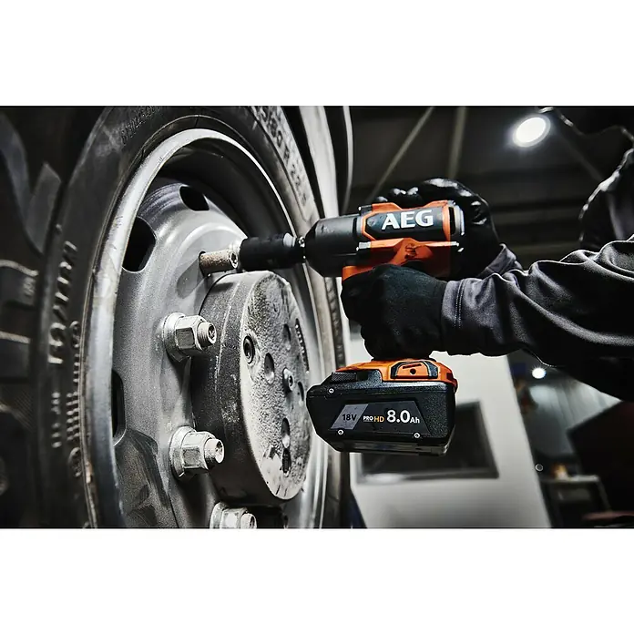 AEG Pro 18V Akku L1880SHD - 18 V, 8 Ah, Li-Ionen - Person benutzt einen orange-schwarzen AEG 18V PROHD 8.0Ah Schlagschrauber an einer Radmutter eines großen Fahrzeugs.