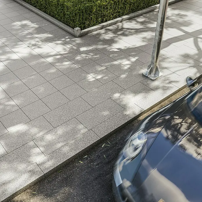 Terrassenplatte G 603 - 80 x 40 x 3 cm, Grau, Granit - Nahaufnahme eines modernen, grauen Pflastersteins mit subtilen Schatten und einem Teil eines Autos im Bild.