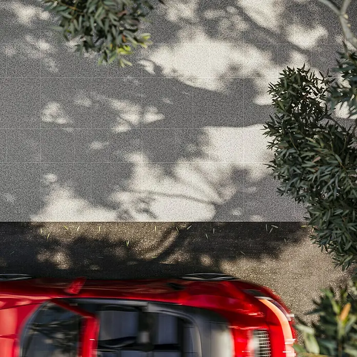Terrassenplatte G 603 - 40 x 40 x 3 cm, Grau, Granit - Draufsicht auf ein rotes Auto auf einem Pflasterweg. Das helle Pflaster wird von Schatten von Bäumen bedeckt.