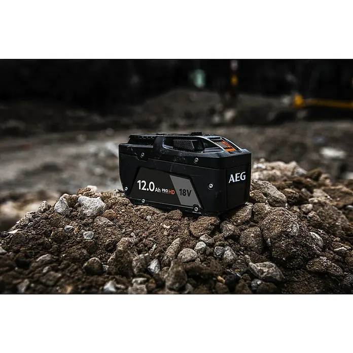 AEG Pro 18V Akku L1812SHD - 18 V, 12 Ah, Li-Ionen - Schwarzer AEG 18V 12.0 Ah PROHD Akku auf einem Haufen Erde und Steinen, was Robustheit suggeriert.