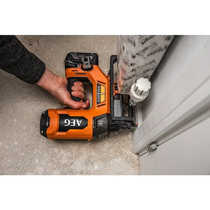 AEG Pro 18V Akku-Nagler B18BN16-0 - 18 V, Ohne Akku, Länge Nagel: 25 mm - 65 mm - Person bedient eine orange-schwarze AEG Nagelpistole zum Befestigen von Leisten an einem weißen Türrahmen.