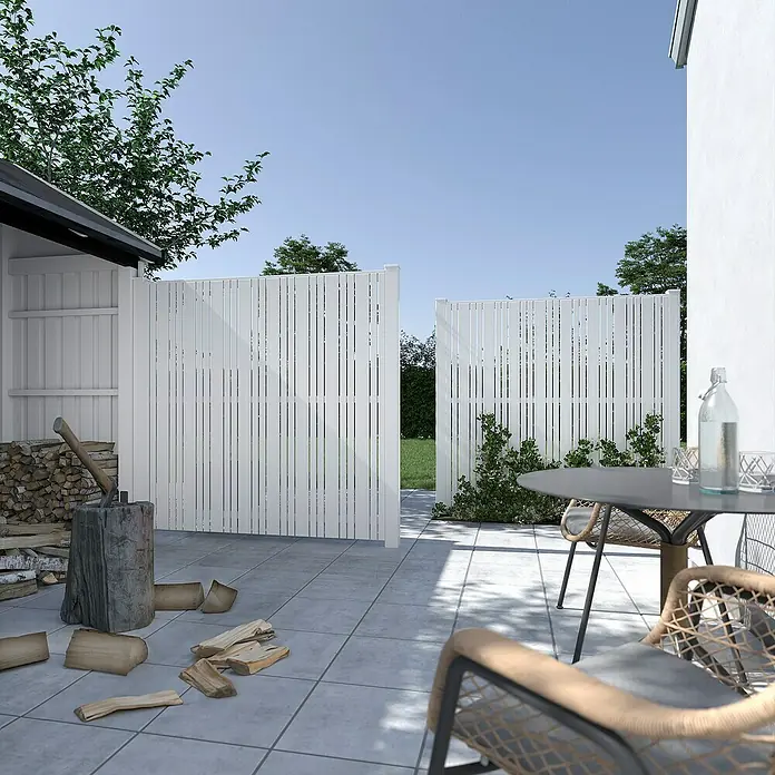 Plus Sichtschutzelement Tangent - 180 x 180 cm, Weiß (RAL 9010) - Eine moderne weiße Zaunanlage mit schmalen, vertikalen Latten umgibt einen Gartenbereich, der mit einem Tisch und Stühlen ausgestattet ist.