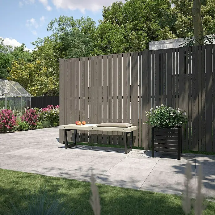 Plus Sichtschutzelement Tangent - 180 x 180 cm, Umbragrau (RAL 7022) - Eine stilvolle Gartenbank mit Kissen und Äpfeln darauf, ergänzt durch einen Blumenkasten mit weißen Blüten vor einem Holzzaun.
