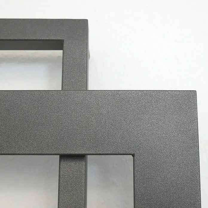 Szagato Designheizkörper Art I - B x H: 600 x 1.800 mm, Wärmeleistung bei Vorlauftemperatur von 75 °C (D: 50): 1.019 W, Moonstone-Grau - Nahaufnahme eines modernen, anthrazitfarbenen Metallrahmens mit quadratischen Aussparungen, ideal als minimalistisches Dekoelement.