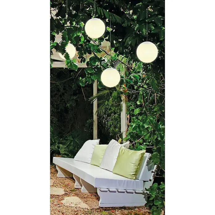 Schwaiger Akku-Pendelleuchte - L x B x H: 20 x 20 x 180 cm, Weiß, RGBW, IP44 - Weiße Kugelleuchten erhellen eine Gartenbank mit Kissen in üppigem Grün.