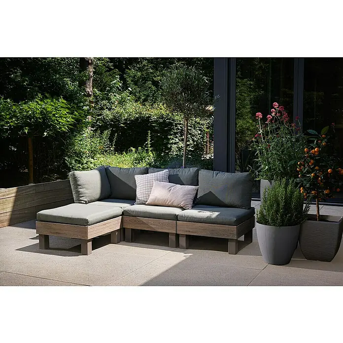 Keter Elements Respaldo de respaldo con cojín - L x An x Al: 60 x 17 x 57 cm, Madera/Verde - Sofá modular de exterior con cojines grises y estructura de madera, rodeado de exuberante vegetación y plantas en macetas. Elegante zona de jardín.