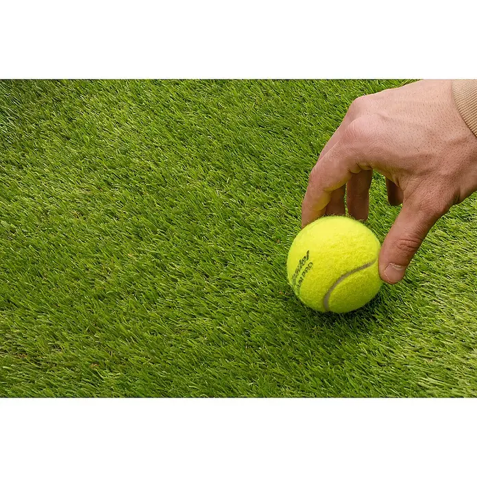 Césped artificial Dresde - 5 x 2 m, Altura del pelo: 30 mm, Densidad: 19.000 puntadas/m² - Primer plano de una pelota de tenis sobre césped artificial sostenida por una mano. Ideal para deportes al aire libre y actividades recreativas.
