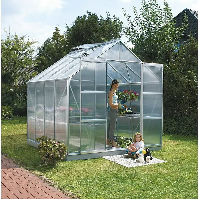 Vitavia Gewächshaus Mars 6700 - Außenmaß inkl. Dachüberstand (B x T): 257 x 258 cm, 4 mm, Aluminium - Ein geräumiges Gewächshaus mit transparenten Wänden, in dem eine Frau arbeitet und ein Kind mit Spielzeug davor sitzt.