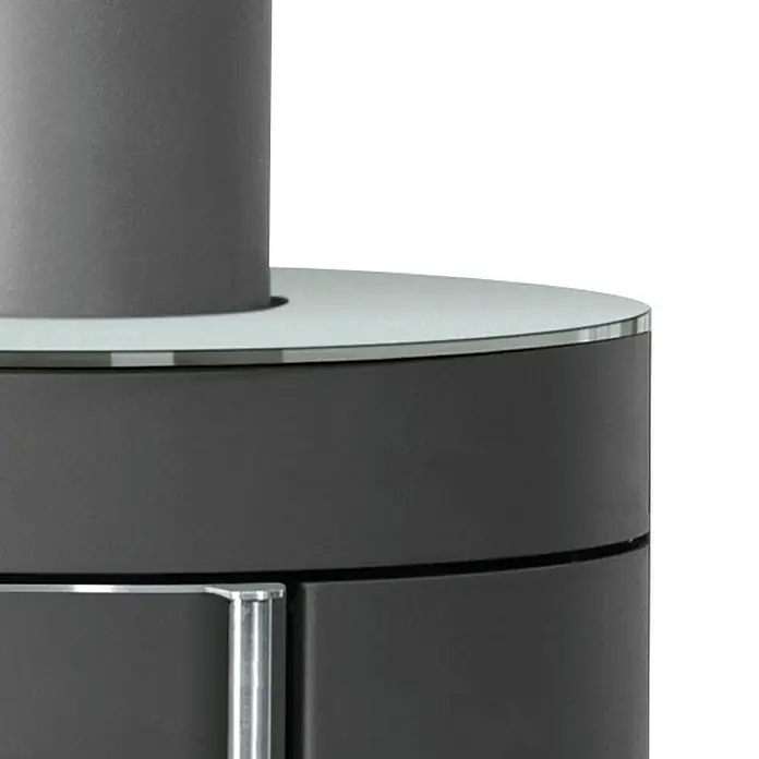 Justus Kaminofen Mino Trios 2.0 - 5,5 kW, Raumheizvermögen: 88 m³, Farbe Verkleidung: Glas, Schwarz - Nahaufnahme eines modernen Ofens mit grauer Oberfläche und stilvollem Design, ideal für gemütliche Wohnräume.