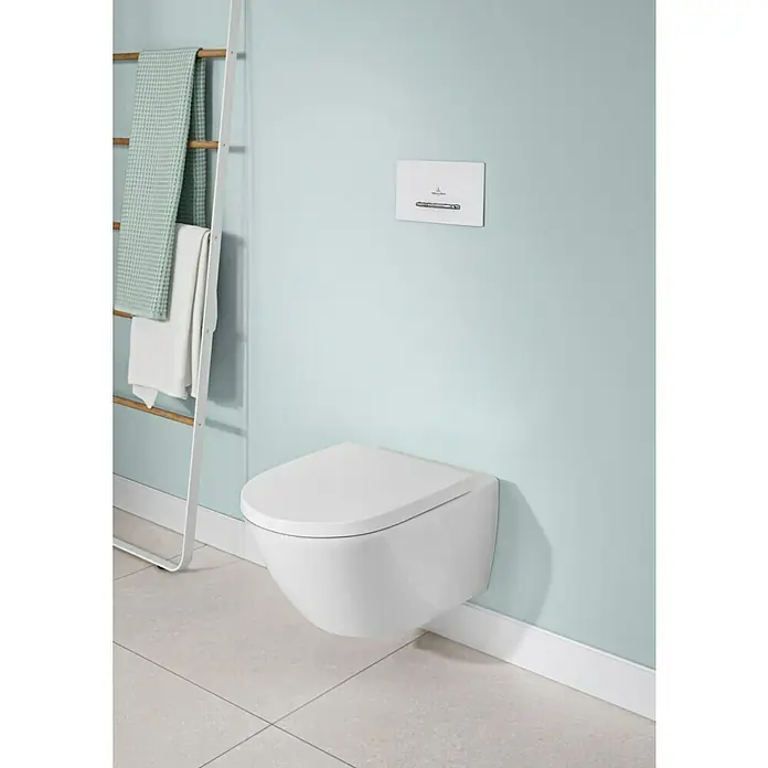 Villeroy & Boch Subway 3.0 WC-Sitz - Duroplast, Weiß Alpin, Mit Absenkautomatik - Weißes wandhängendes WC mit Spülplatte in einem hellblauen Badezimmer mit Fliesenboden und Handtuchleiter.