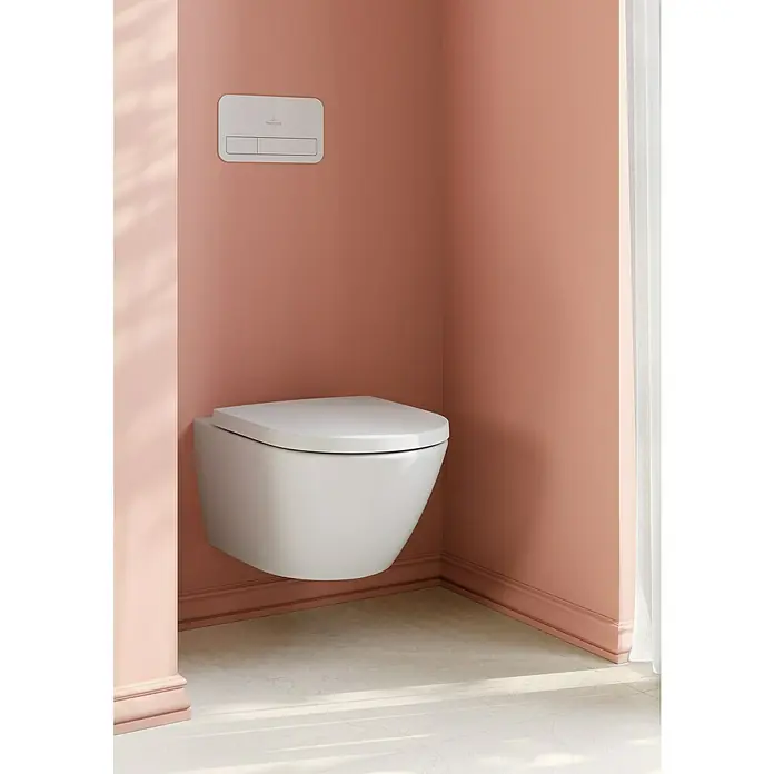 Villeroy & Boch Subway 3.0 WC-Sitz - Duroplast, Weiß Alpin, Mit Absenkautomatik, Mit antibakterieller Glasur - Weißes wandhängendes WC mit passender Spülplatte an einer warmen, pfirsichfarbenen Wand.