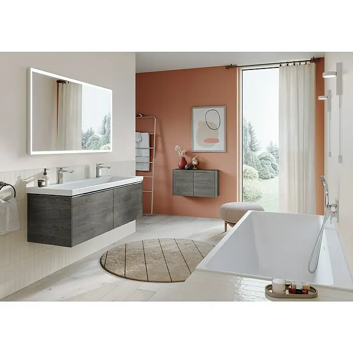 Villeroy & Boch Subway 3.0 Seitenschrank - B x T x H: 72,8 x 25,6 x 42,3 cm, Stone Oak, DIN Anschlag: Links/Rechts, Farbe Griff: Aluminium glänzend - Ein modernes Badezimmer mit einem großen Spiegel über einem Waschtisch mit grauen Holzfronten und einer freistehenden Badewanne.