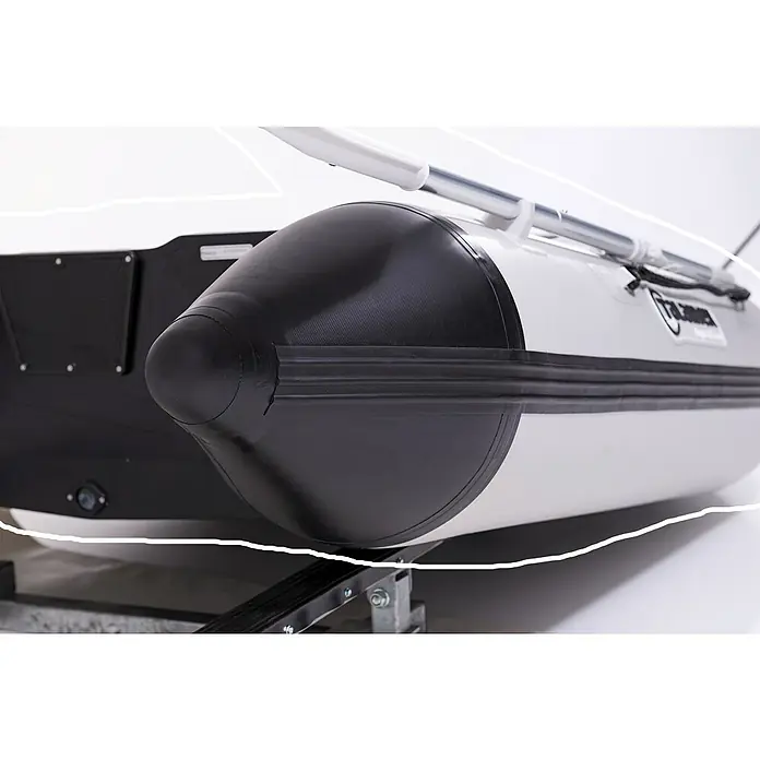 Talamex Schlauchboot Luftboden Aqualine QLA270 - L x B: 270 x 152 cm, Tragkraft: 410 kg, Geeignet für: 3 Personen - Nahaufnahme eines Schlauchboots mit schwarzem Bug und weißen Seiten, das auf einem Anhänger ruht.