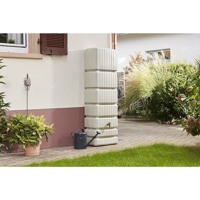4rain Regenspeicher Slim - 350 l, Sandbeige, 1 Stk. - Ein stilvoller, stapelbarer Wassertank in Beige steht neben einem Haus, komplett mit einem Hahn und einer Gießkanne für die Gartenarbeit.