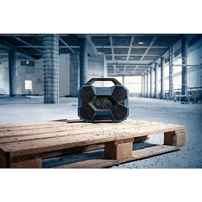 Bosch Professional AMPShare 18V Bluetooth-Lautsprecher GPB 18V-6 C - 18 V, Ohne Akku - Blau-schwarzes, robustes Bosch Baustellenradio auf einer Holzpalette in einer Bauumgebung.
