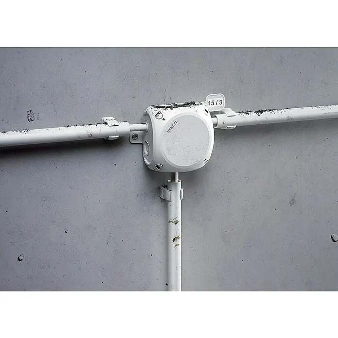 Hensel  Abzweigkasten Kabel DK0600G - 130 x 130 x 77 mm - Nahaufnahme einer Hensel-Abzweigdose an einer Betonwand, mit daran befestigten Rohren. Industrielles Design und robuste Bauweise.