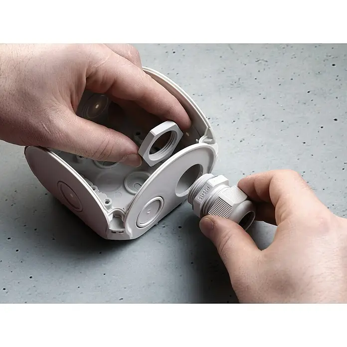 Hensel  Abzweigkasten Kabel DK0600G - 130 x 130 x 77 mm - Nahaufnahme der Montage einer weißen Abzweigdose mit Kabelverschraubung und Mutter für die Elektroinstallation.