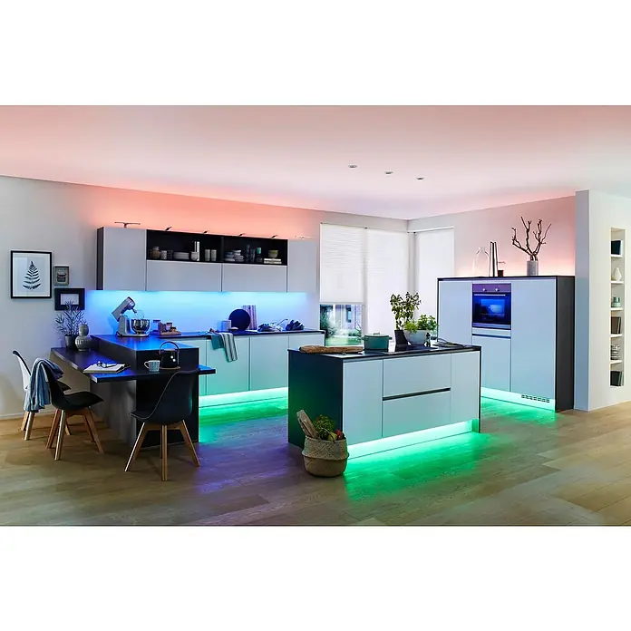 Paulmann MaxLED 500 LED-Band-Set Basisset Zigbee - 300 cm, RGBW, 29 W, 1.050 lm, 230 V - 240 V - Moderne Küche mit farbiger Beleuchtung unter den Schränken und der Insel, die eine gemütliche Atmosphäre schafft. Die Küchengeräte sind stilvoll integriert.